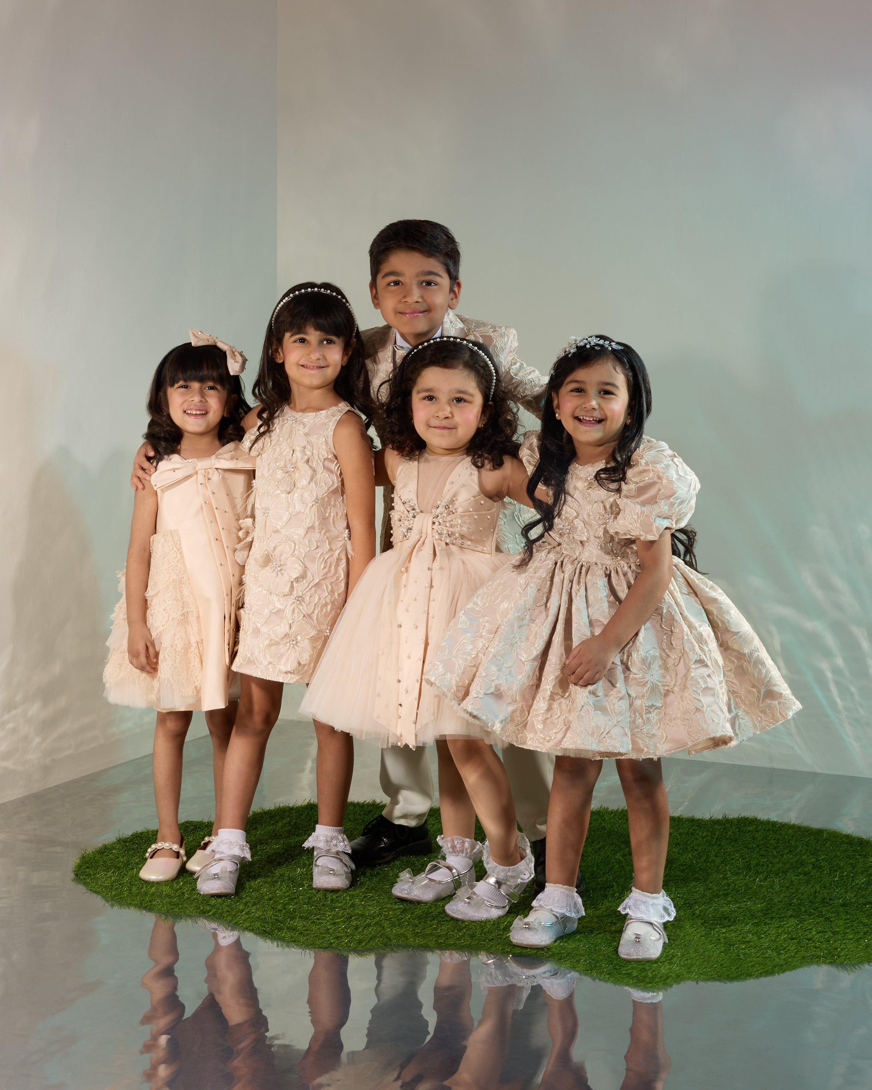 Five kids in elegant formal wear pose.